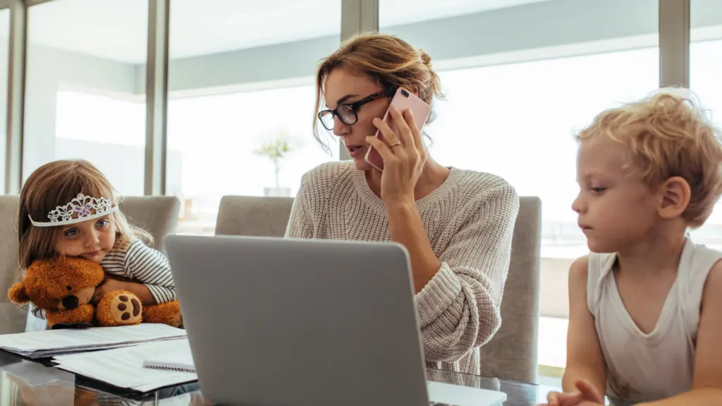 Woman remote working with 2 kids to look after